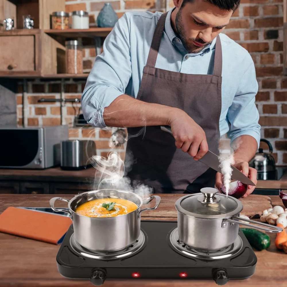 Man cooking with electric portable cooktop in rustic kitchen cutting vegetables.