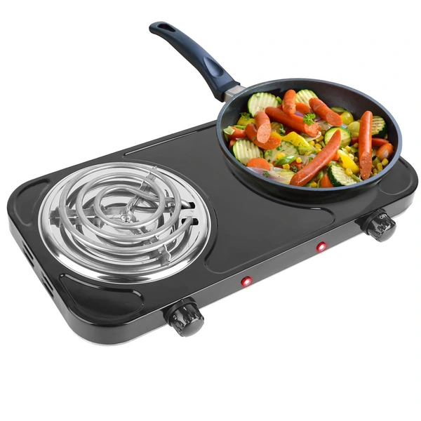 Electric stovetop with a frying pan cooking mixed vegetables and sausages.