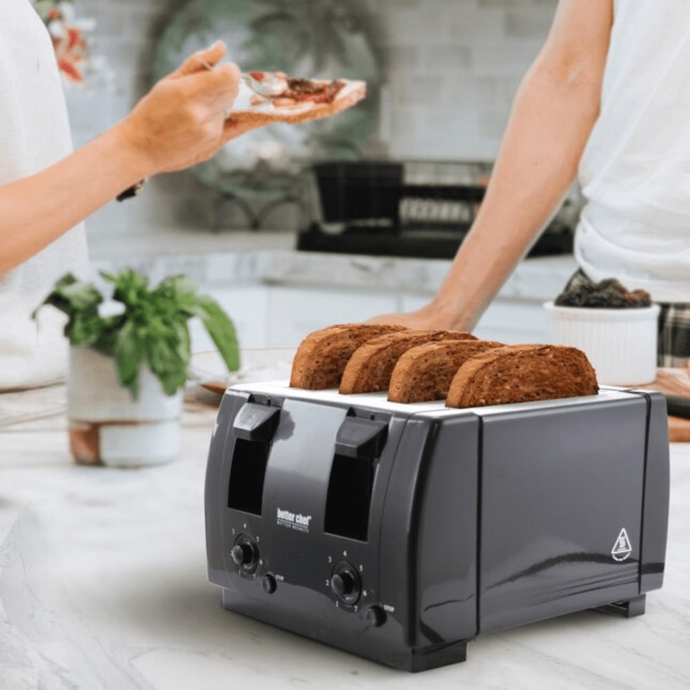 Two people in a kitchen making toast with a black Better Chef four-slice toaster