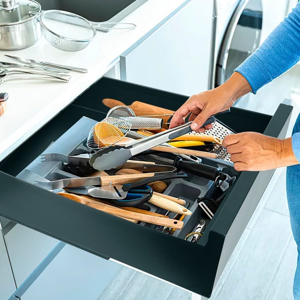 Person organizing kitchen utensils in a drawer