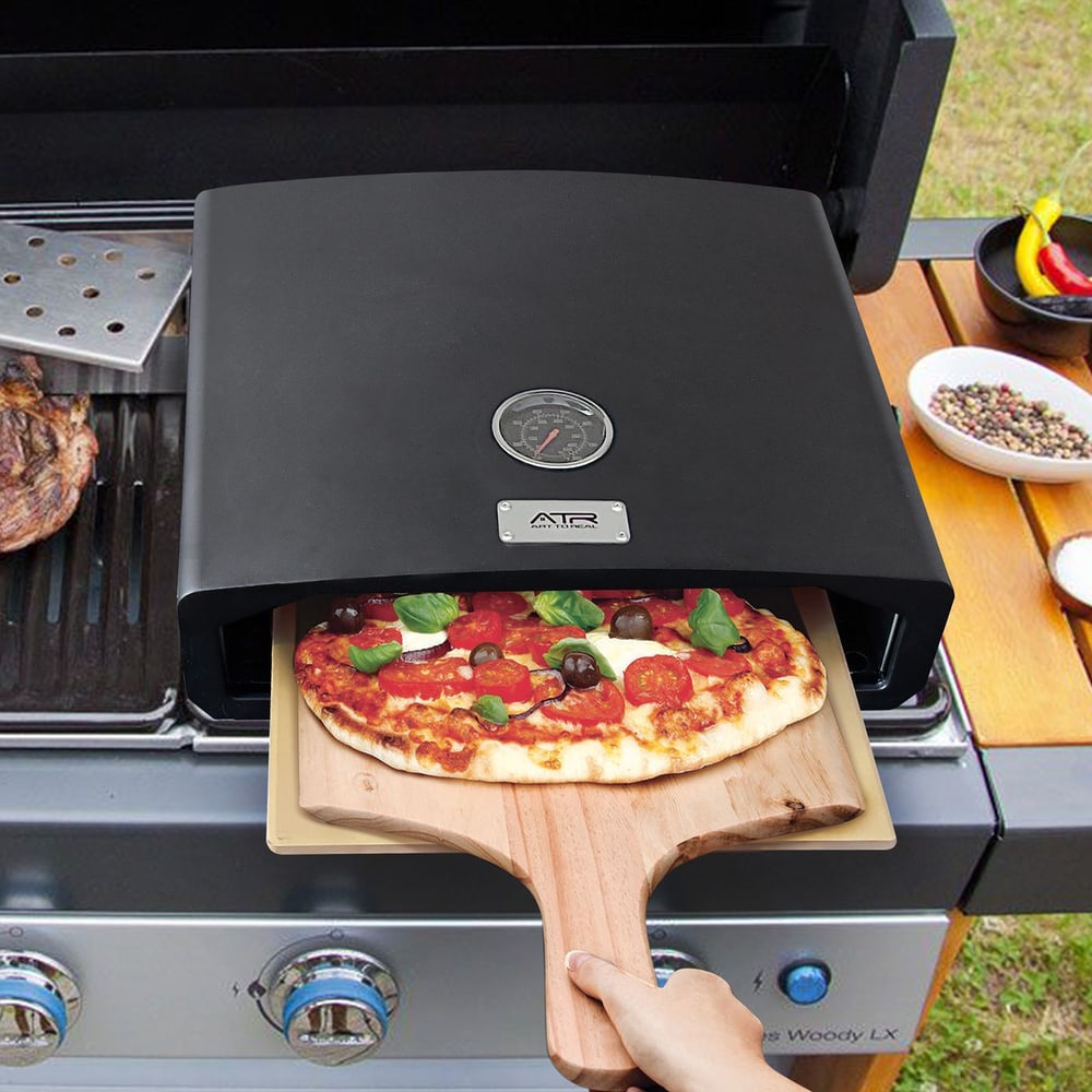 Pizza being pulled from an outdoor grill pizza oven on a wooden peel.