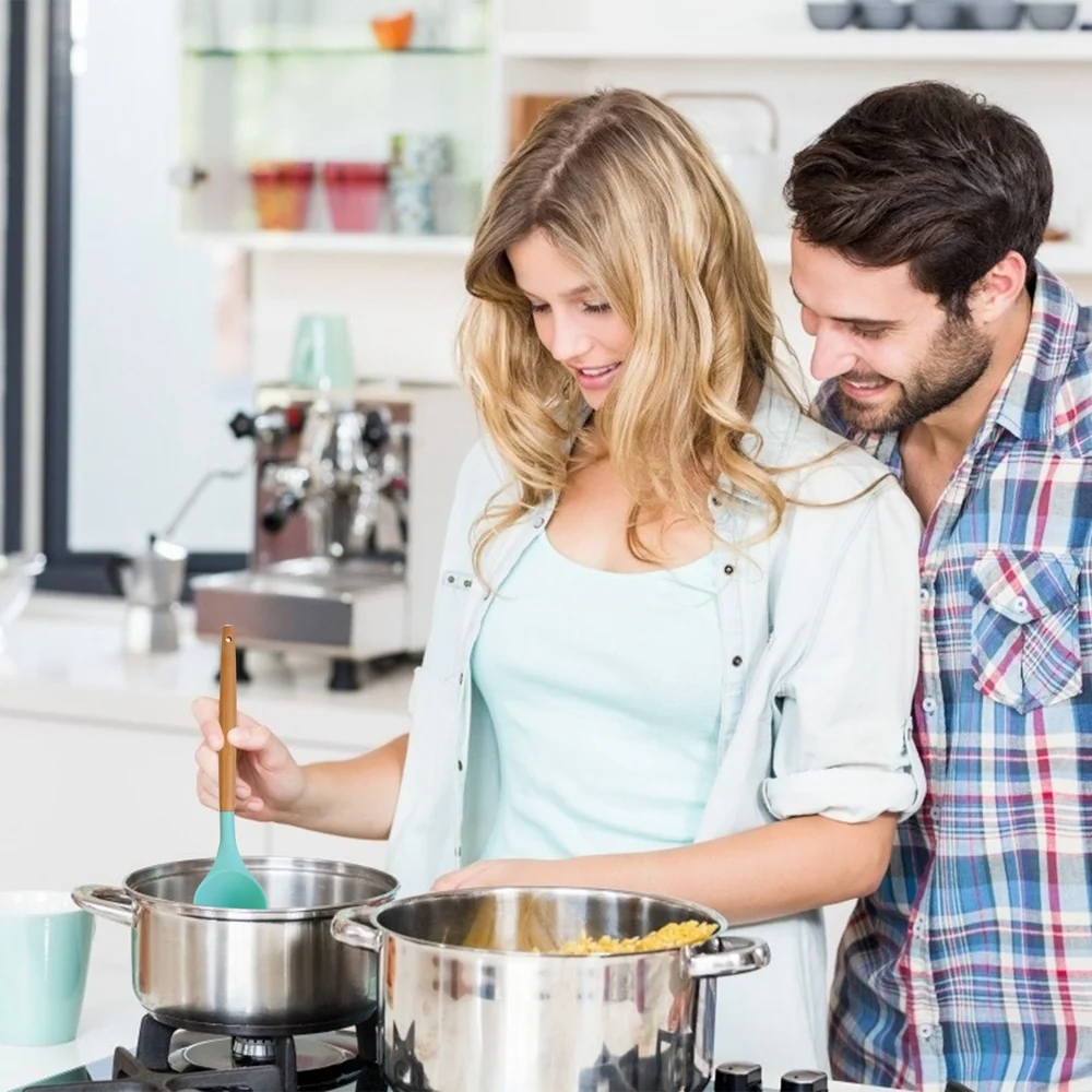 Two people cooking together in a modern kitchen, using a saucepan and wooden spoon.