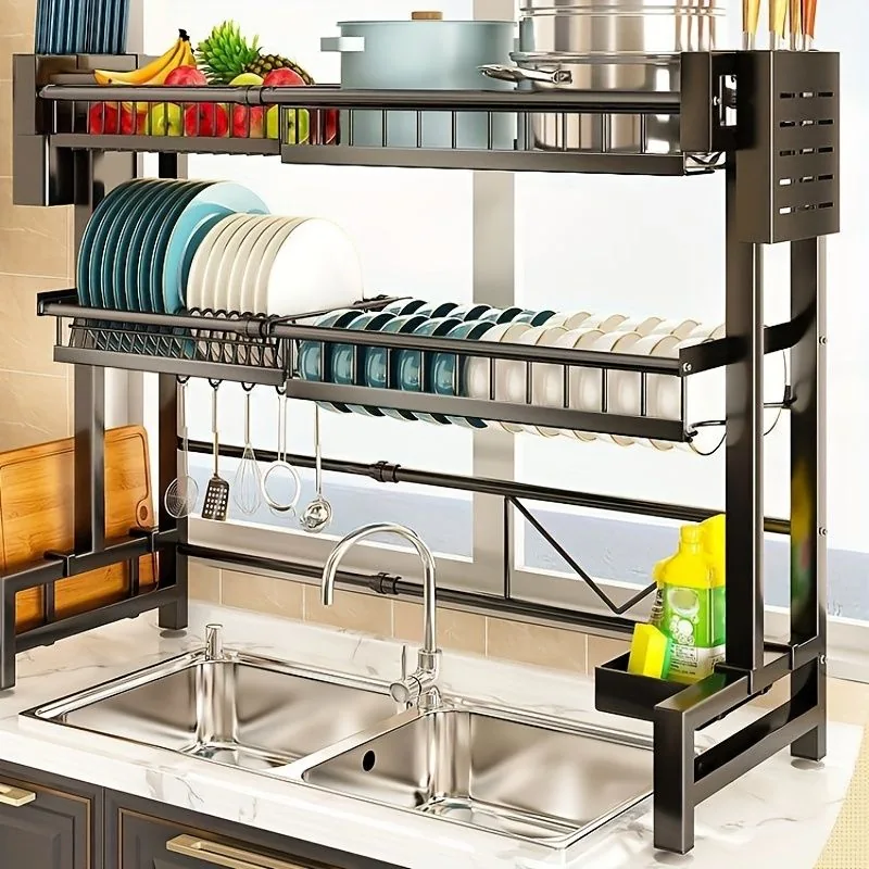 Modern kitchen sink with a stainless steel double basin, overhead dish rack, organized utensils, fruit, cutting board, and cleaning supplies.
