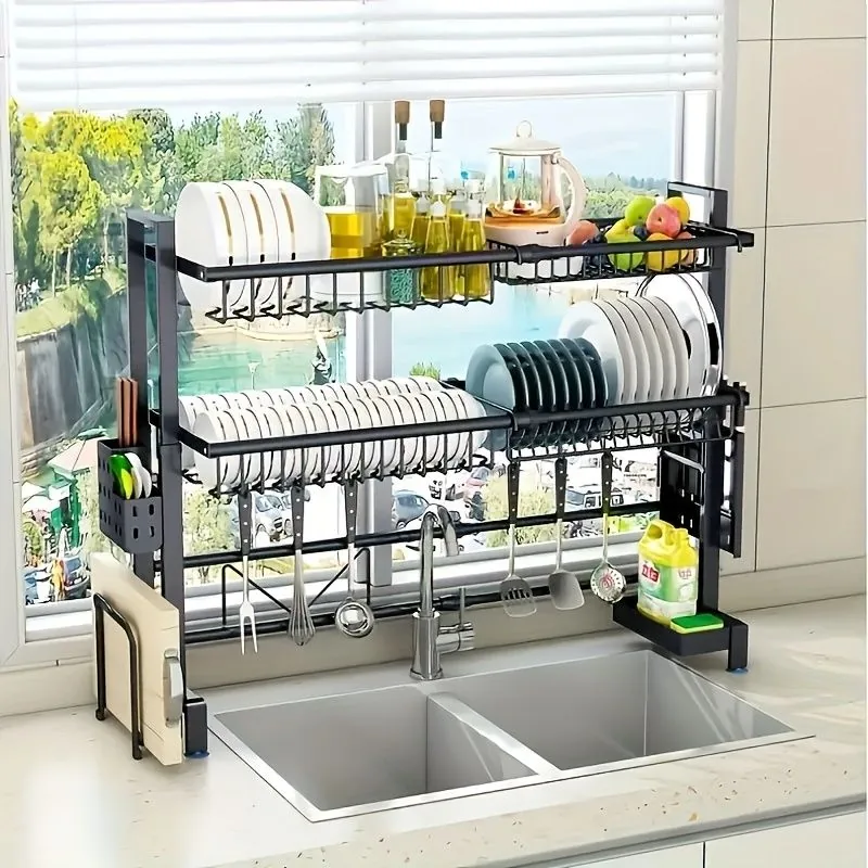 Kitchen sink with over-the-sink dish drying rack filled with dishes and kitchen supplies, next to a sunny window.