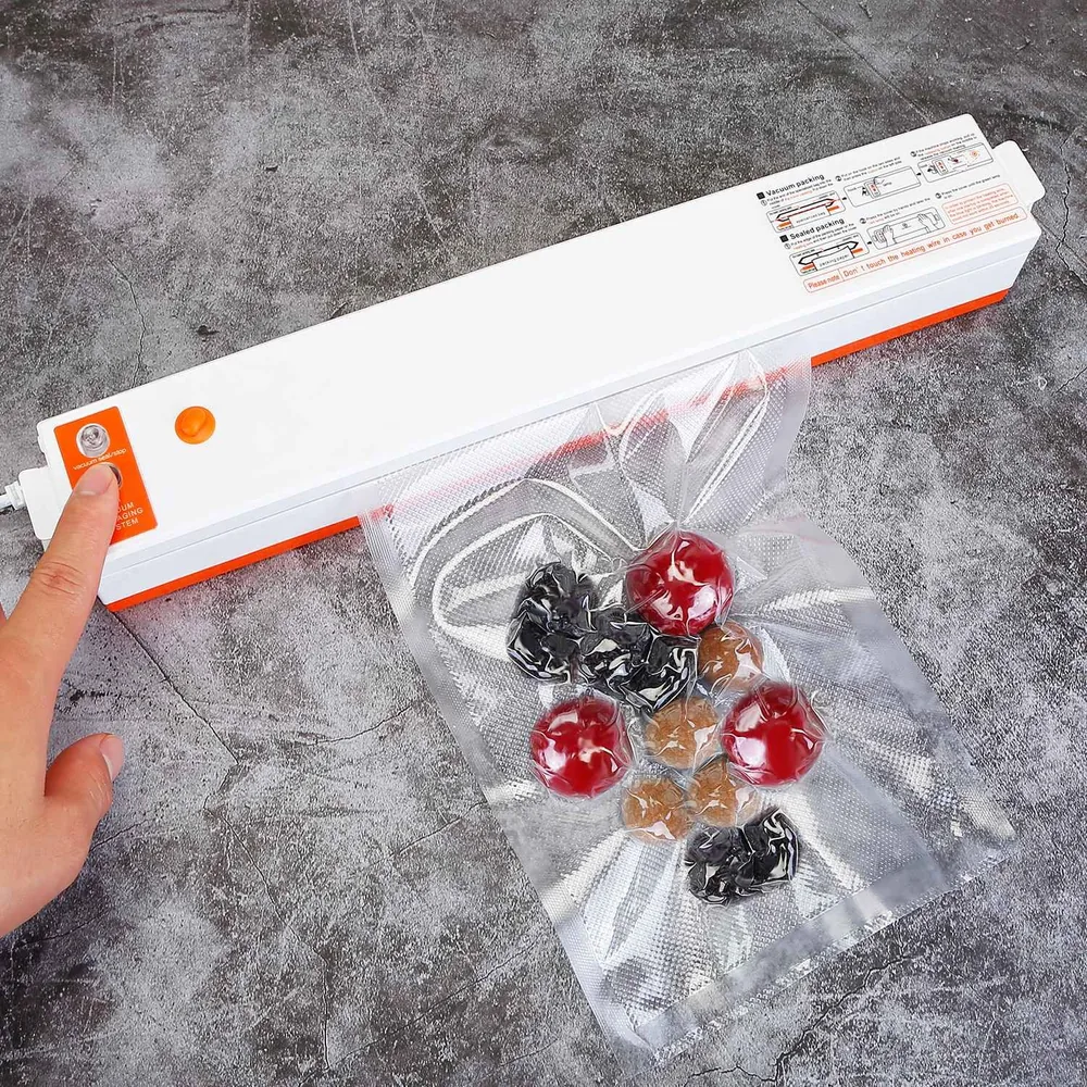 Vacuum sealer machine sealing fresh vegetables in vacuum bag on grey countertop.