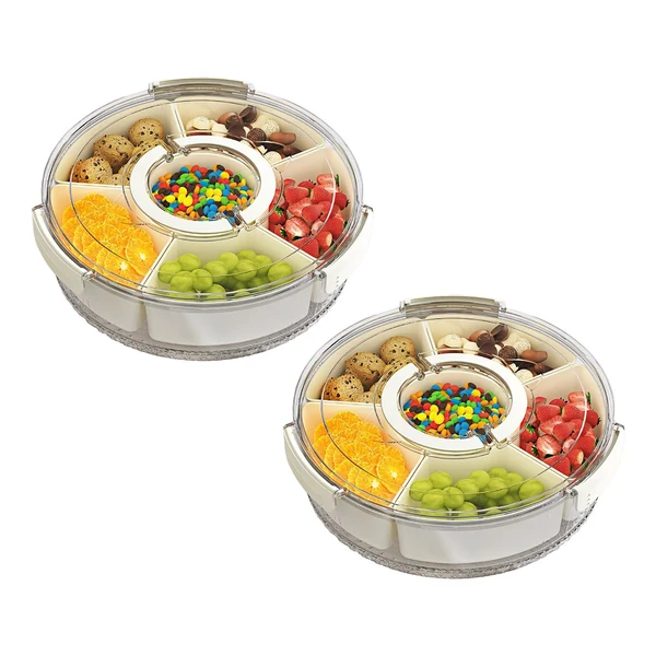 Two circular plastic snack trays with sections containing oranges, grapes, strawberries, cookies, chocolates, and colorful candies